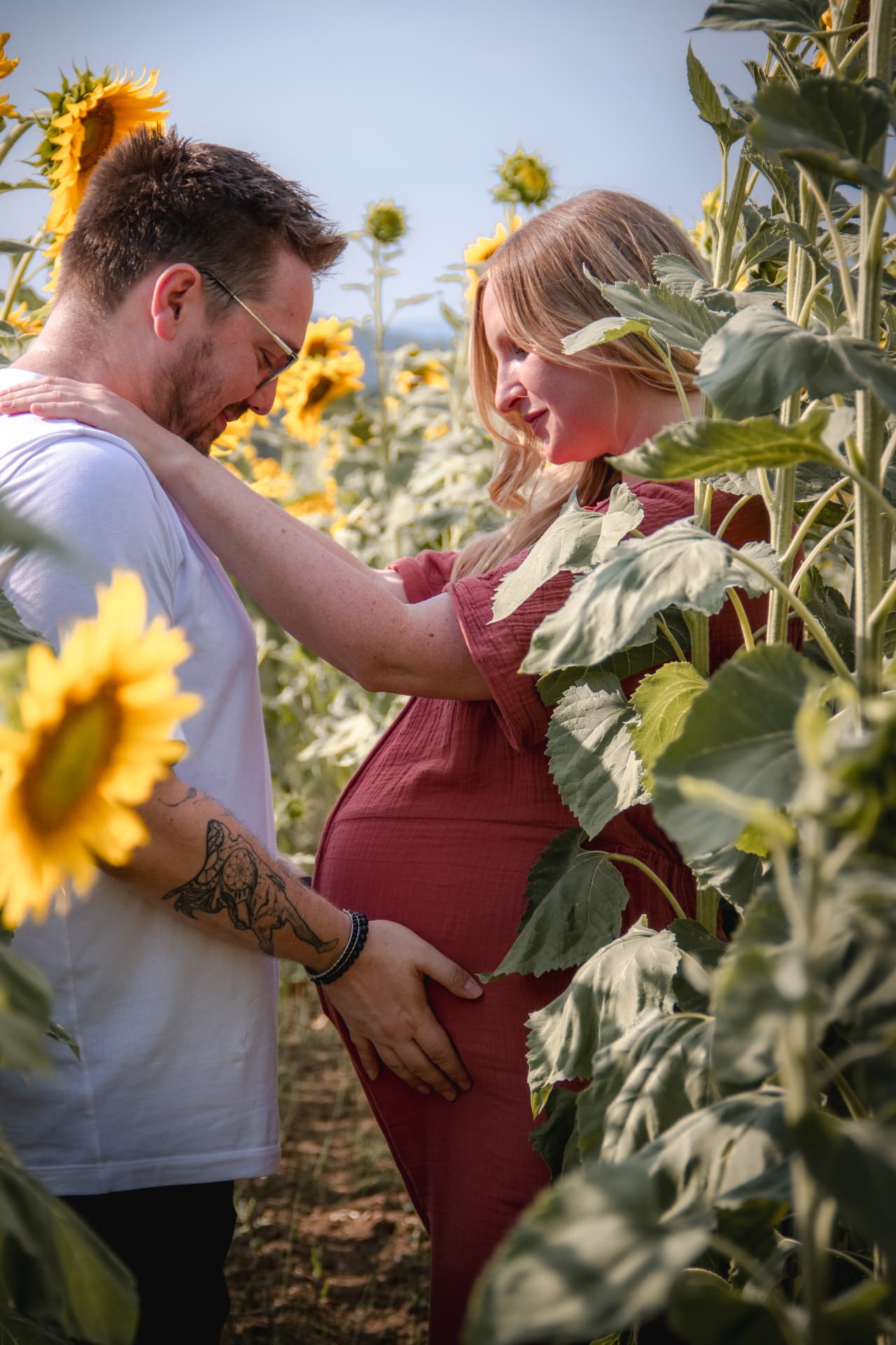 Couple attendant un bébé dans un champ de tournesols
