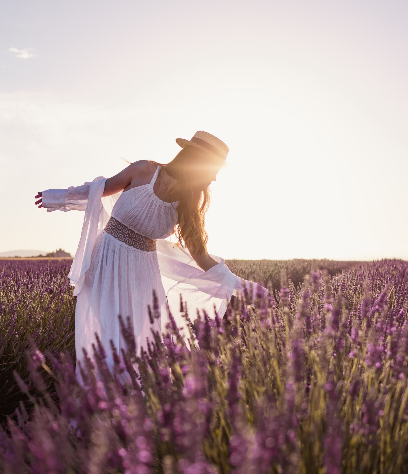 Femme en robe blanche dansant dans la lavande à contre-jour