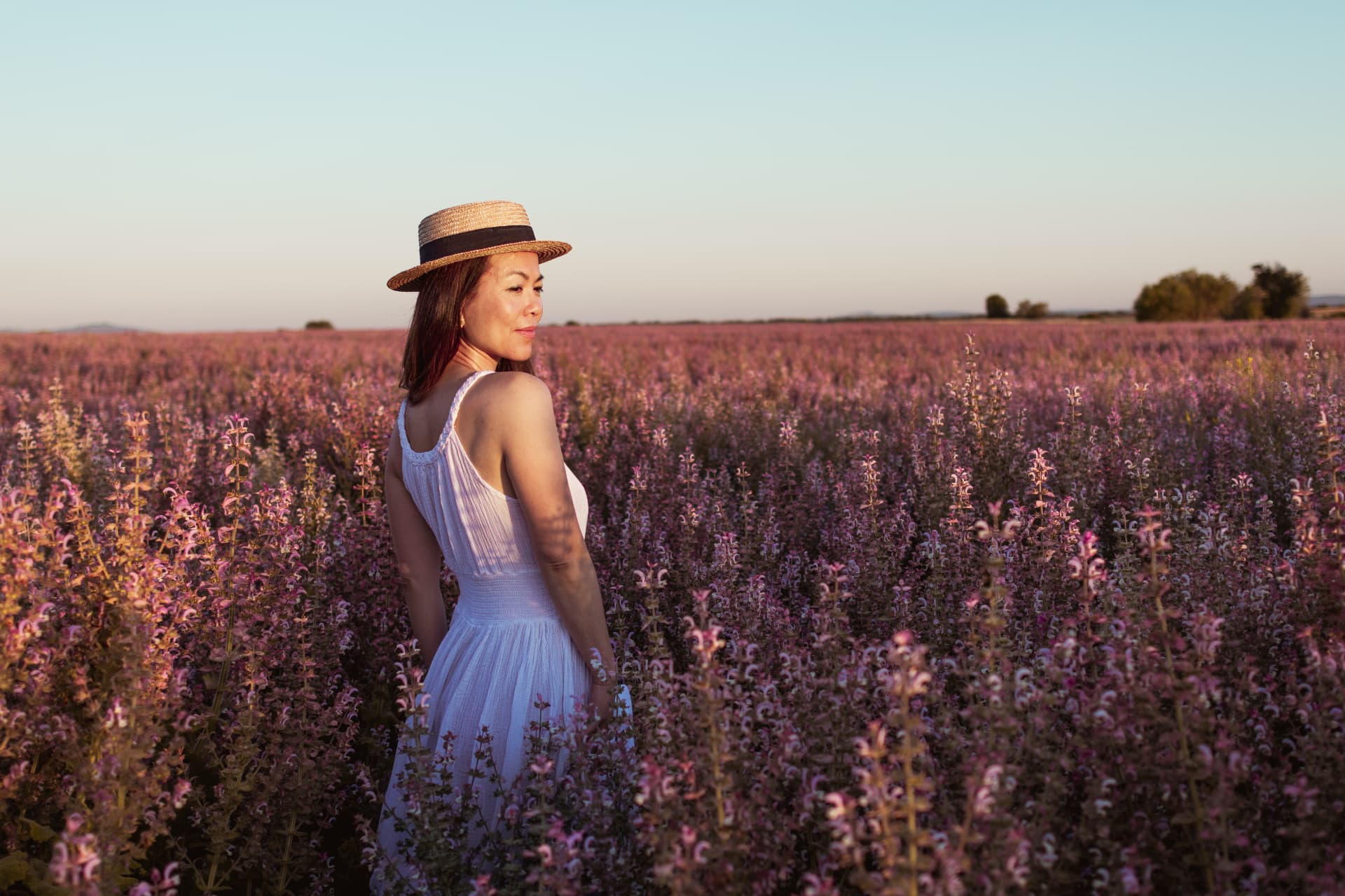 Femme en robe blanche dans un champ de sauge sclarée au crépuscule