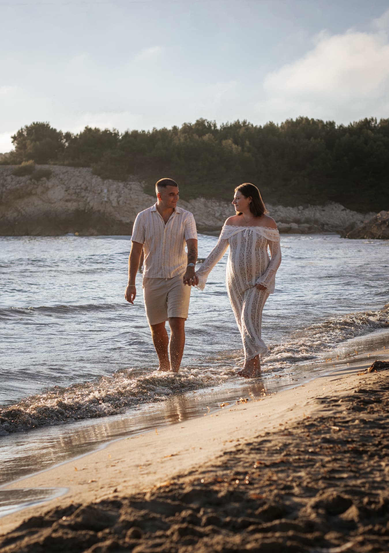 Couple enceinte marchant main dans la main au bord de l'eau