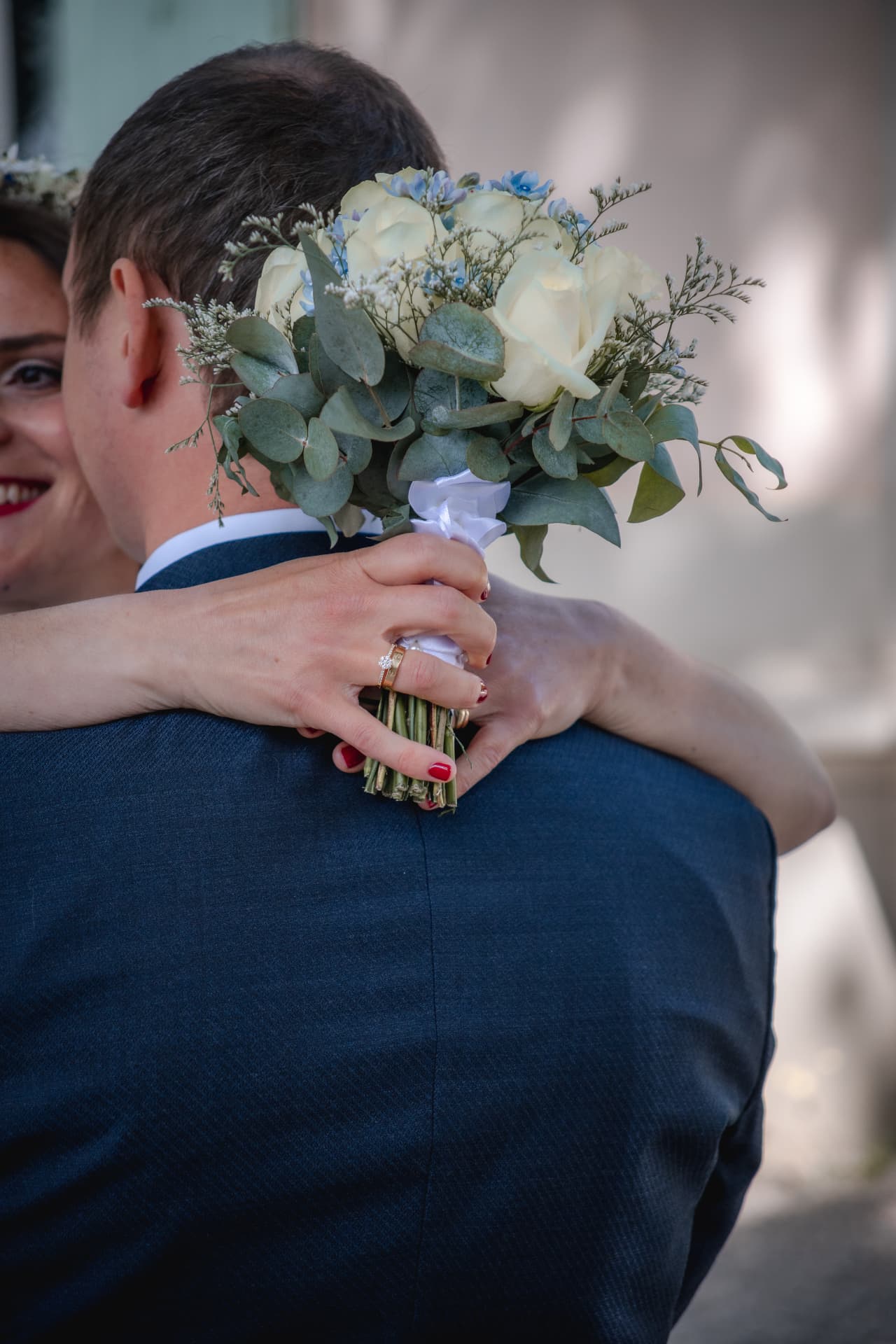 Mariée enlaçant son mari, bouquet de roses blanches à la main