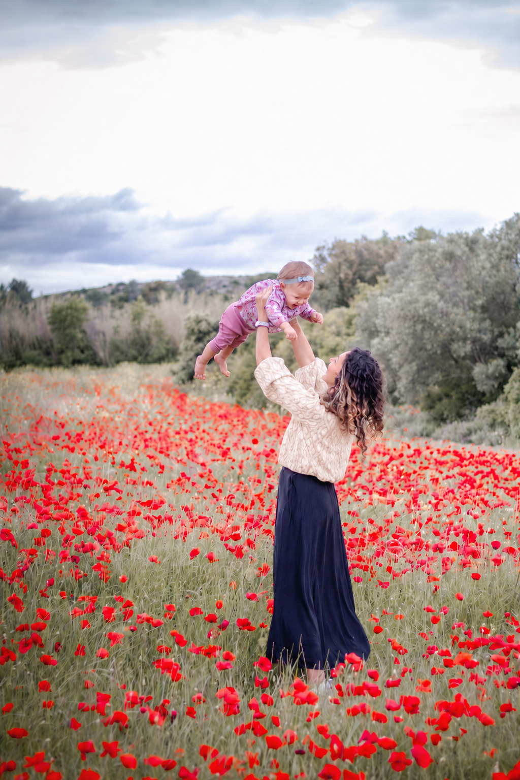 Maman soulevant son bébé dans un champ de coquelicots en Provence