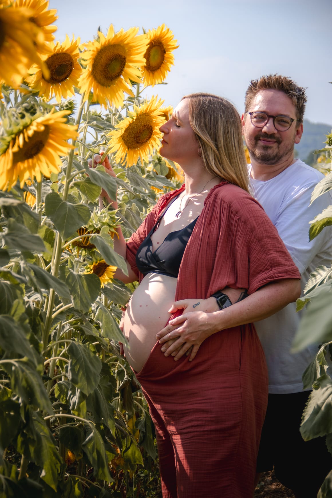 Pregnant woman with partner in sunflower field