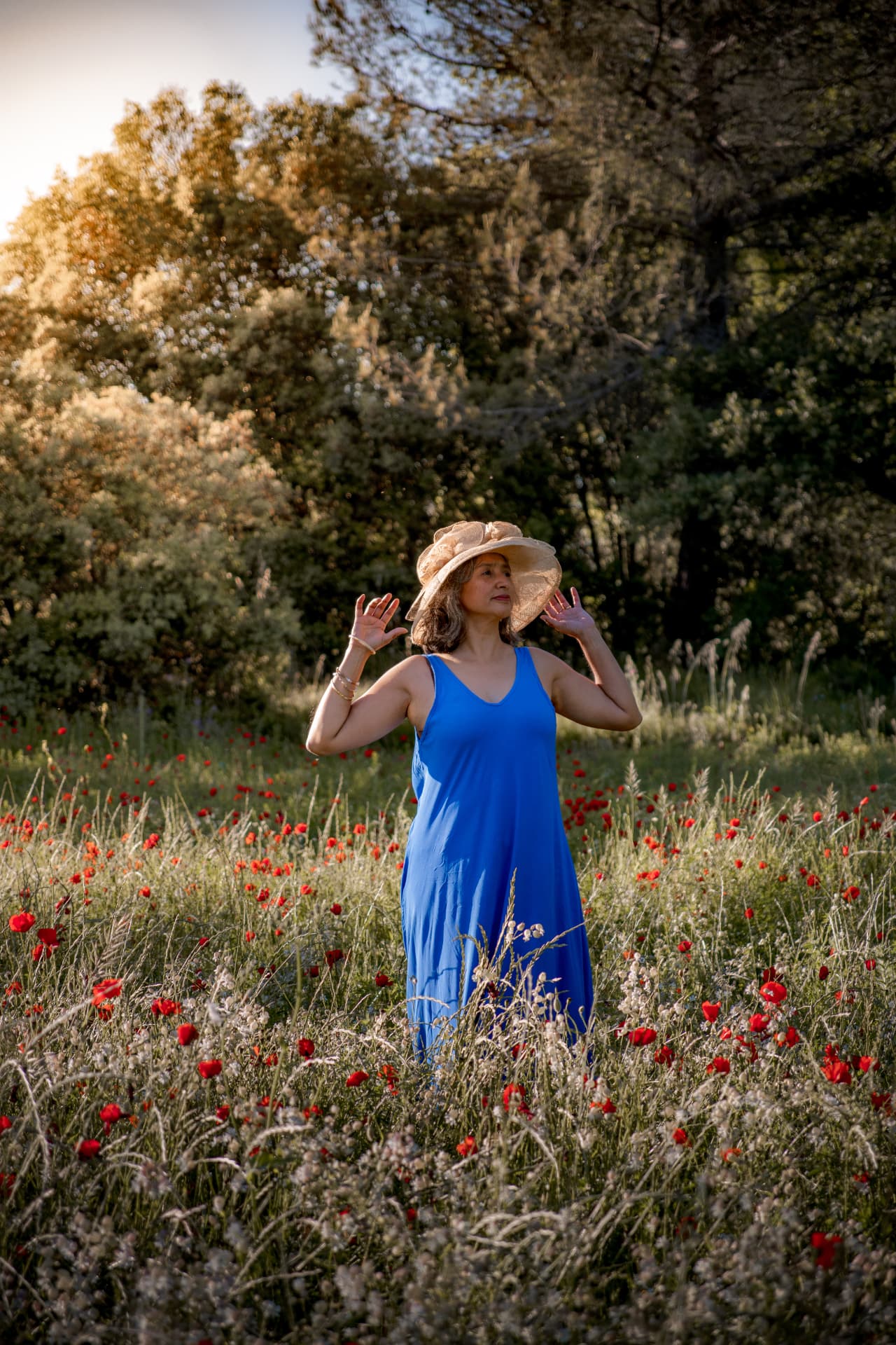 Femme en robe bleue au chapeau dans une prairie de coquelicots