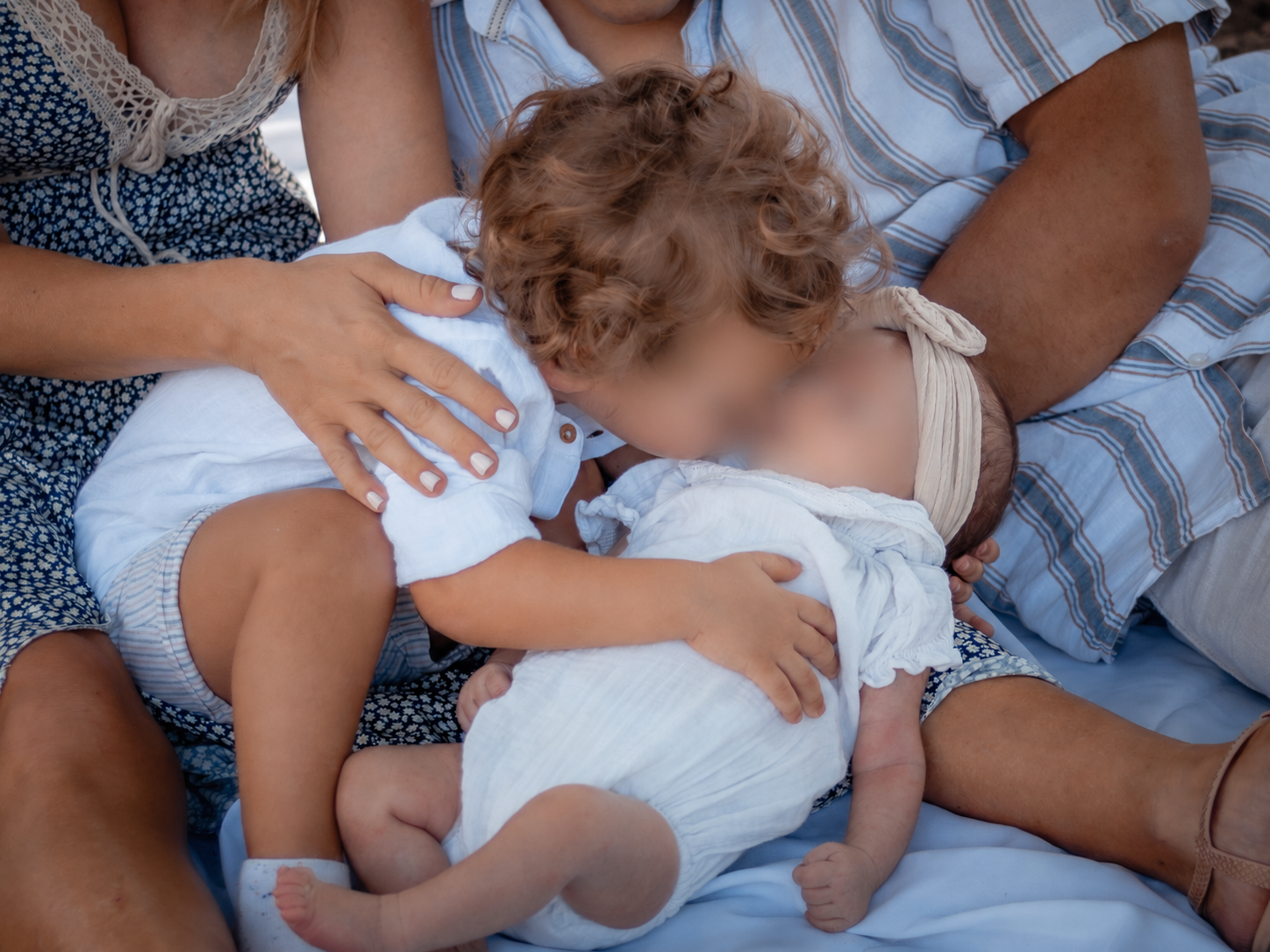 Grand frère embrassant son nouveau-né blotti dans les bras de sa maman