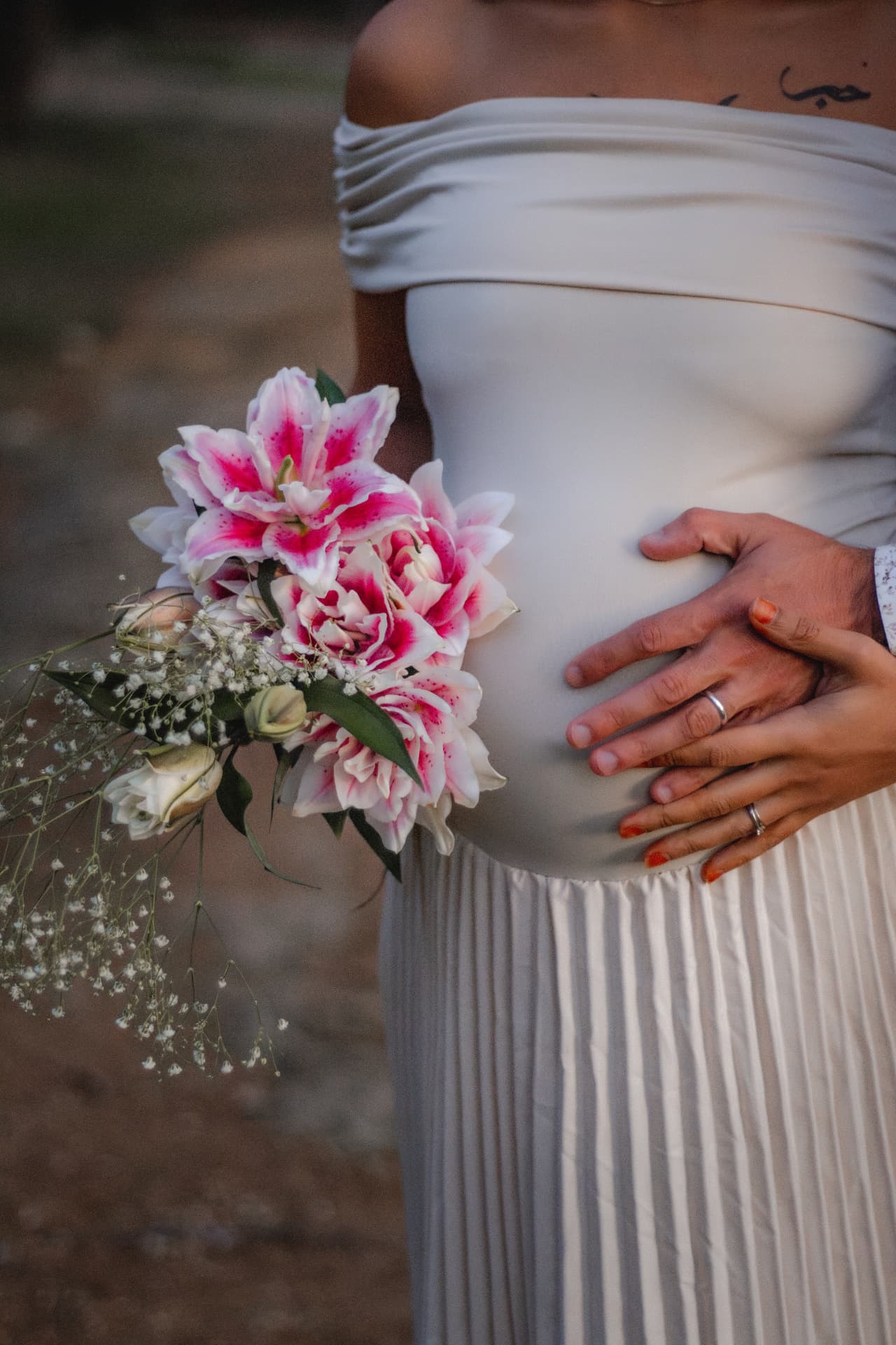 Bouquet de lys et mains posées sur le ventre, séance grossesse
